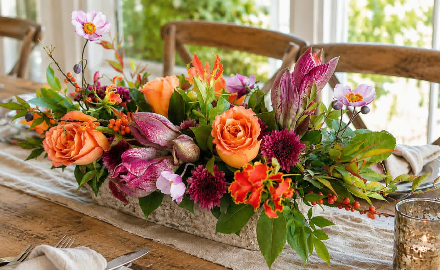 Colorful orange, peach, and purple centerpiece on a wooden table
